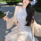 A person wearing a light blue Qi Lolita Dress with floral skirt and cardigan.