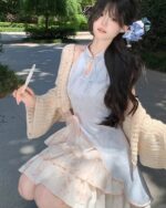 A person wearing a light blue Qi Lolita Dress with floral skirt and cardigan.