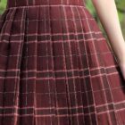 Close-up of a maroon JK Plaid Skirt with white checks, featuring a pleated design.