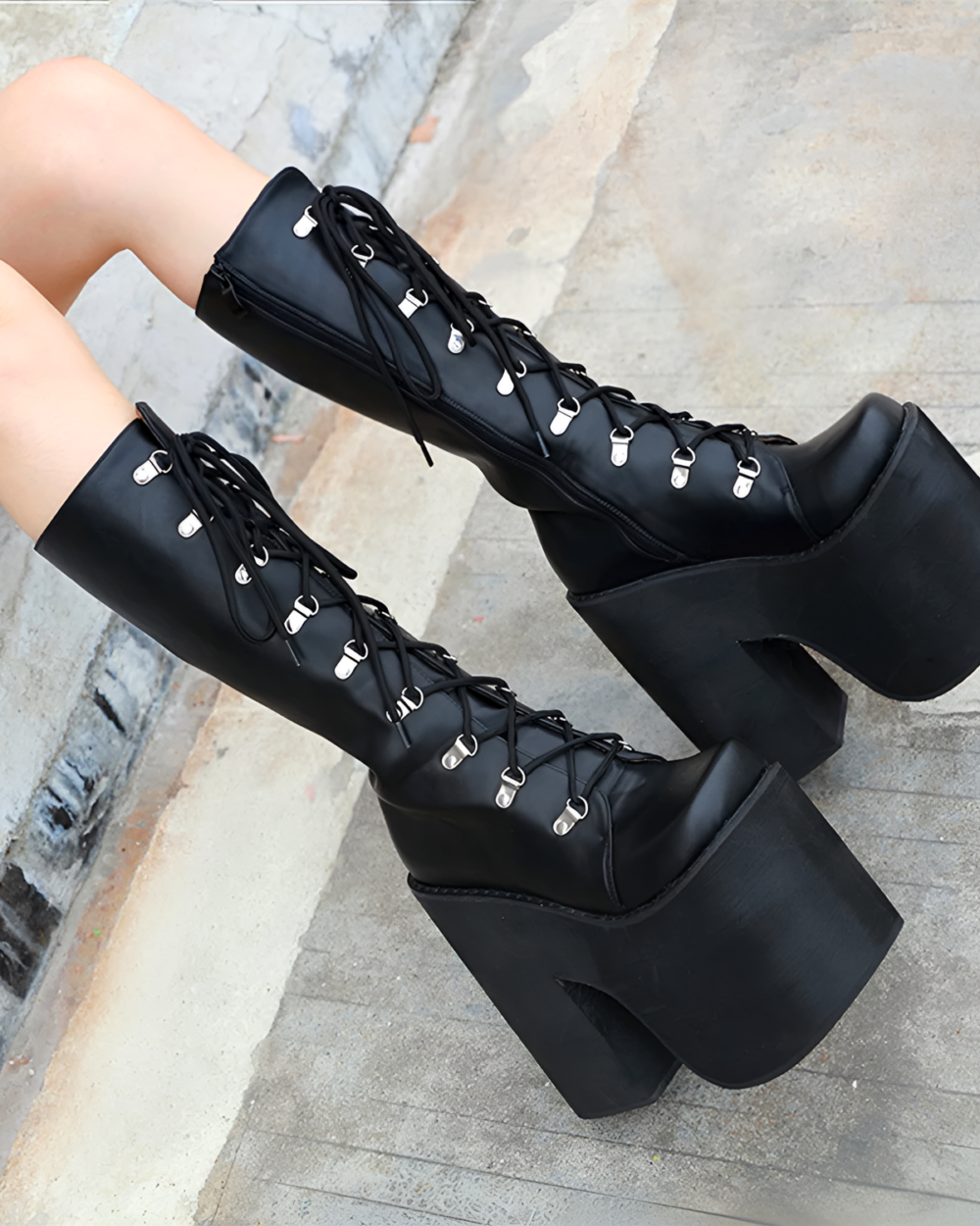 Black lace-up goth platform boots with a thick block heel. High-top design, shown on a model's legs.