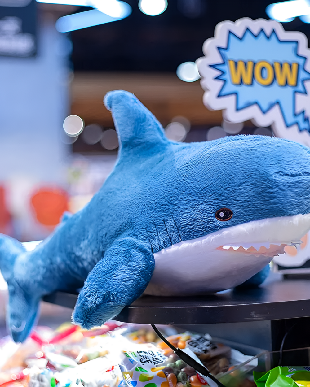 Alfred the Shark product photo 1 Blue shark plushie, Alfred the Shark, displayed on a wooden table.