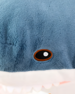 Close-up of Alfred the Shark plushie, featuring a dark eye and white teeth.