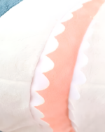Close-up of Alfred the Shark plushie showing its pink teeth.