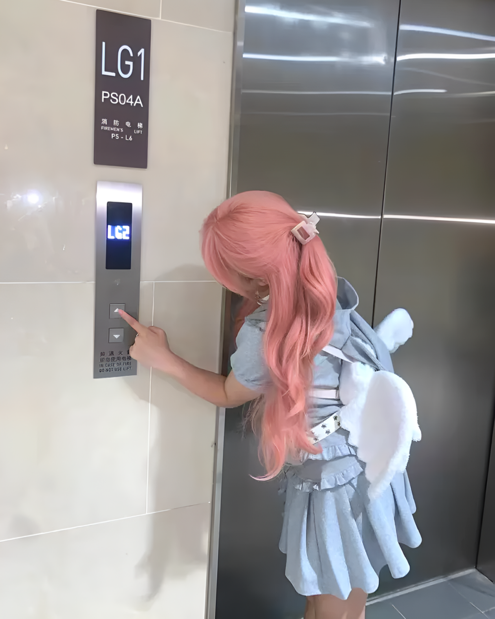 Person wearing an angel wing backpack, featuring plush wings and a blue outfit.