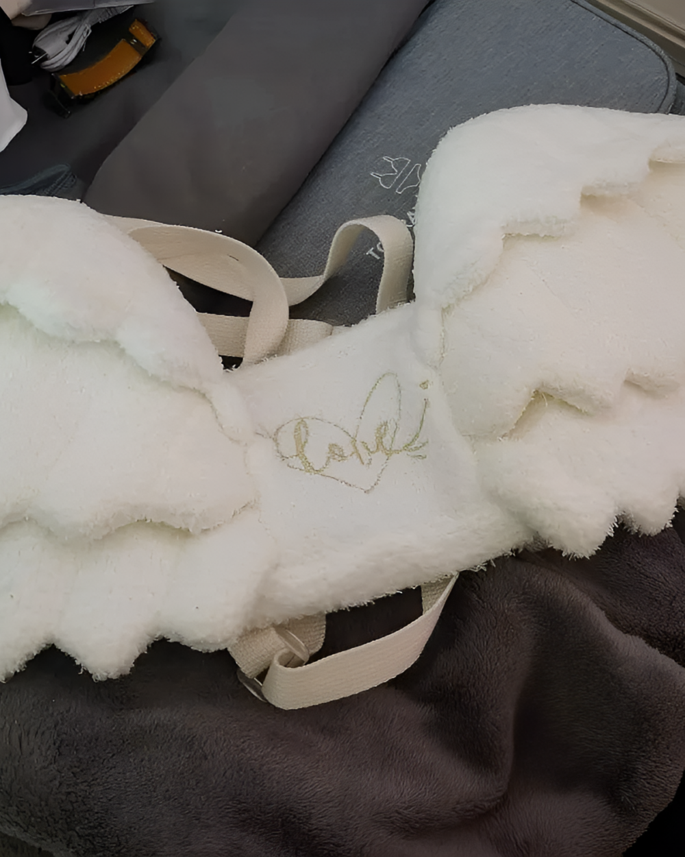 White angel wing backpack with attached straps and a small heart embroidery.