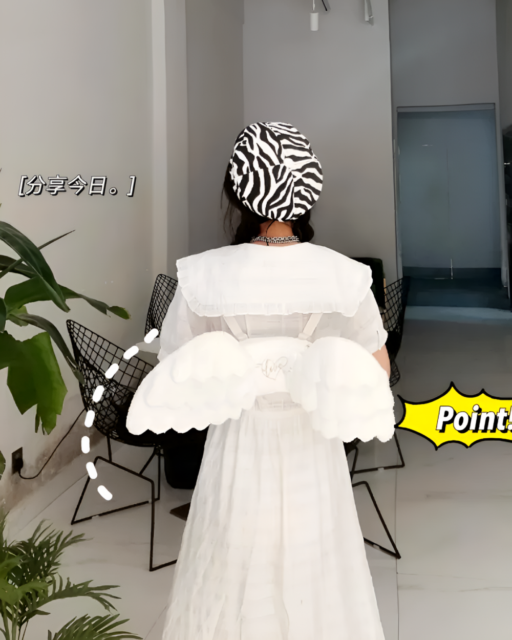 White angel wing backpack displayed with a dress and zebra-print headwrap.