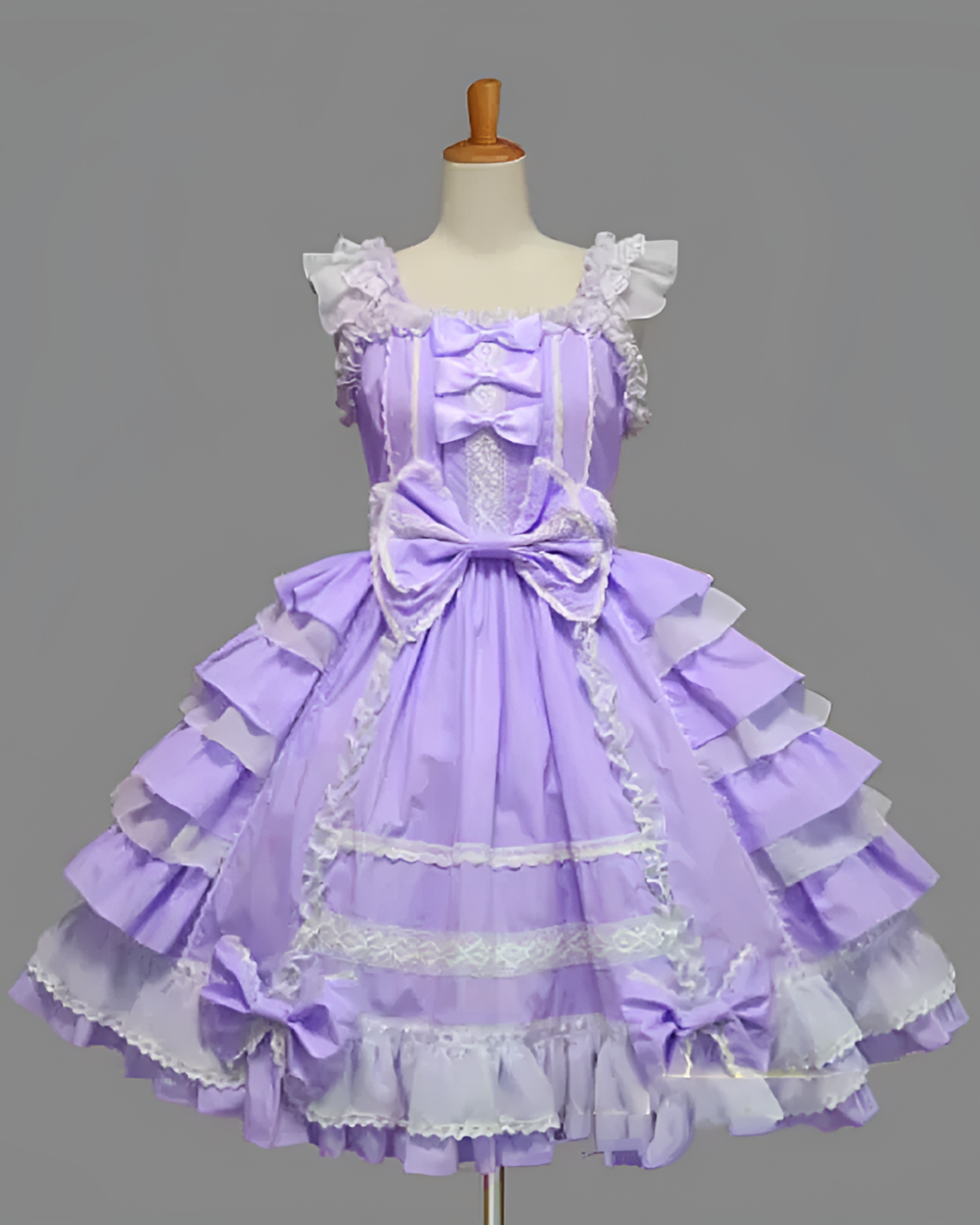 Purple Hime Lolita dress with ruffled details and lace trim, displayed on a mannequin. The Bloom Princess JSK features a bow at the waist.