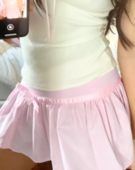 Pink pleated mini skirt with ruffles, a coquette aesthetic.