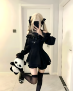 Model wearing a black Bowed Mini Dress with long sleeves and lace details, a Gothic Lolita dress paired with black stockings.