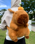 Person wearing a brown Capybara Plushie backpack with a carrot accessory, outdoor shot.