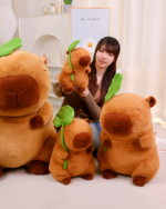 Photo of a woman holding a brown capybara plushie with a leaf on its head, with other capybara plushies nearby.