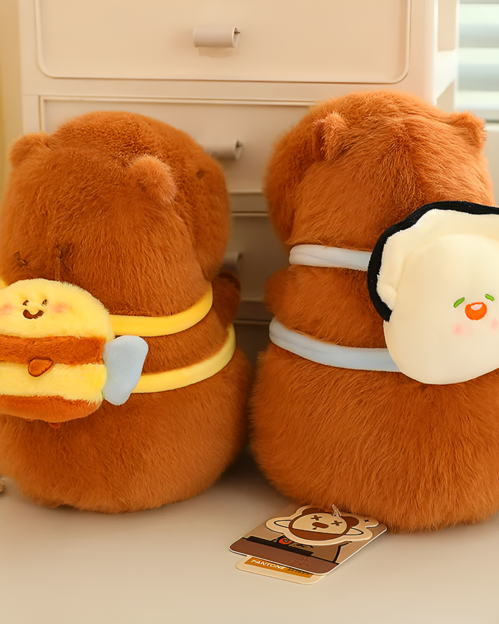 Two brown capybara plushies with explorer outfits, including a bandana and a tag. A cute capybara plushie collection.
