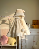 Cream colored Cat Eared Winter Cloak on a dress form, featuring a fluffy hood and tie closures.