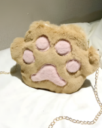 Close-up of a tan cat paw purse with a chain strap and pink lining.