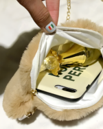 Close-up of a beige cat paw purse showing its interior, zipper, and gold lining.