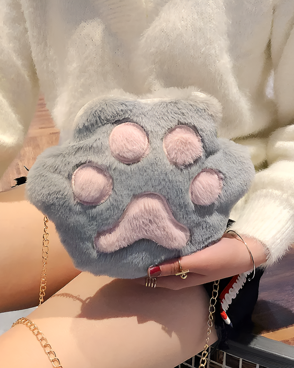 Close-up of a gray cat paw purse with a chain strap, featuring plush fur detailing.