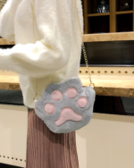Close-up of a gray and white cat paw purse with a gold chain strap.