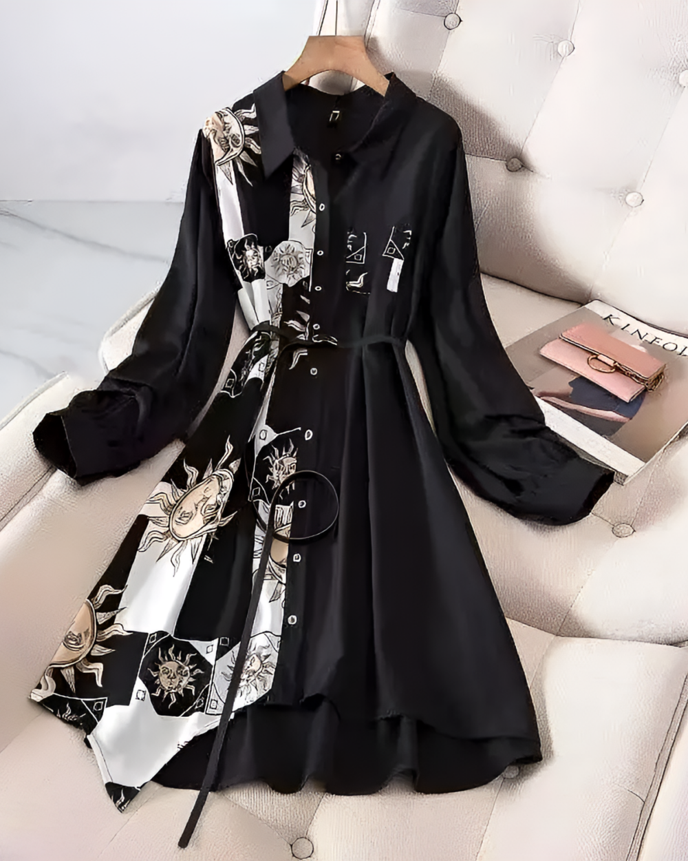 Black and white celestial witchcore dress with a sun and moon print, long sleeves, and a collared neckline. Styled on a couch.