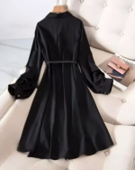 Black long-sleeve celestial witchcore dress with a tie waist, displayed on a couch.