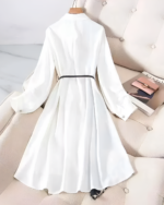 Back view of a white long-sleeved celestial witchcore dress with a tie waist. Hanging on a hanger.