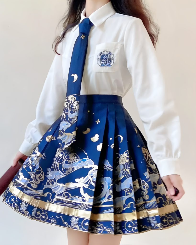 A model wearing a white shirt and navy blue celestial pleated skirt with gold accents and a wave pattern.