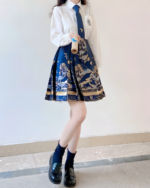 Woman wearing a white blouse and navy blue celestial pleated skirt with a patterned design. Dark socks and black shoes.