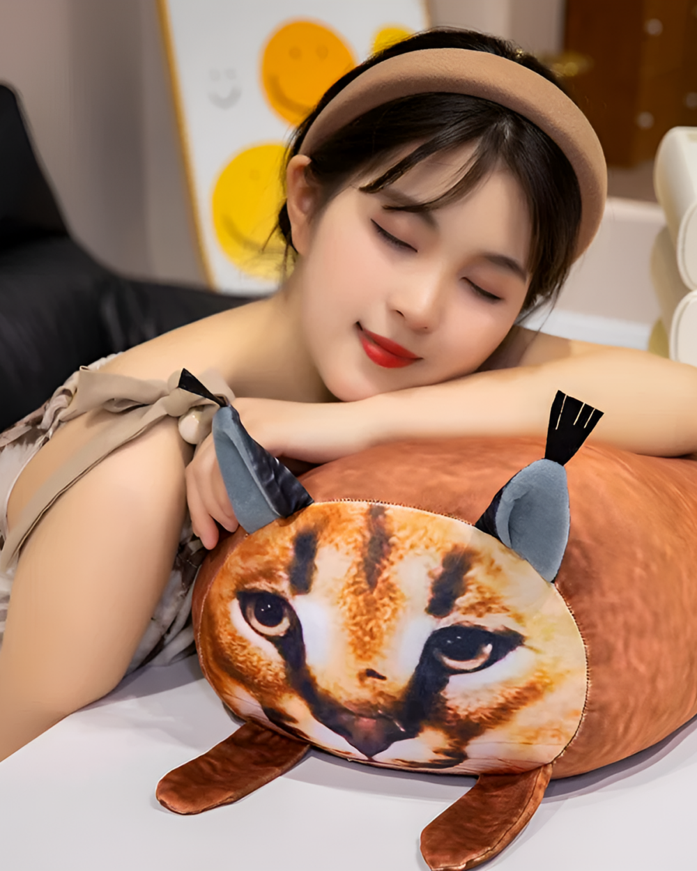 Chonky Big Floppa plushie resting on a pillow, with a woman hugging it.