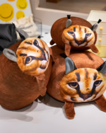 Chonky Big Floppa plushie displayed on a shelf with other plush toys.