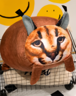 Brown Chonky Big Floppa plushie with realistic face and ears, resting on a wire rack.