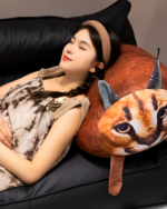 A Chonky Big Floppa plushie is nestled against a woman sleeping on a couch.