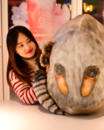 Chonky Realistic Palla's cat plush resting on a surface, with a person interacting with it.