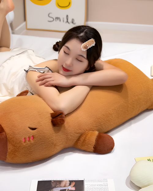 A person sleeping while hugging a large, brown capybara plushie. Soft toy for kids & adults.