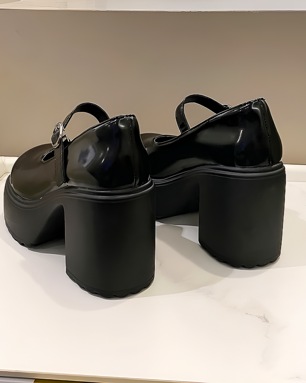 Black Chunky Mary Janes with a thick platform heel and ankle buckle, displayed on a white surface.