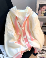 Creamy pink knit sweater with heart buttons and a striped cuff.