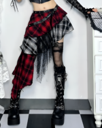 Model wearing a crimson and black pleated goth punk skirt with black boots and fishnet stockings. Asymmetric design with plaid pattern.