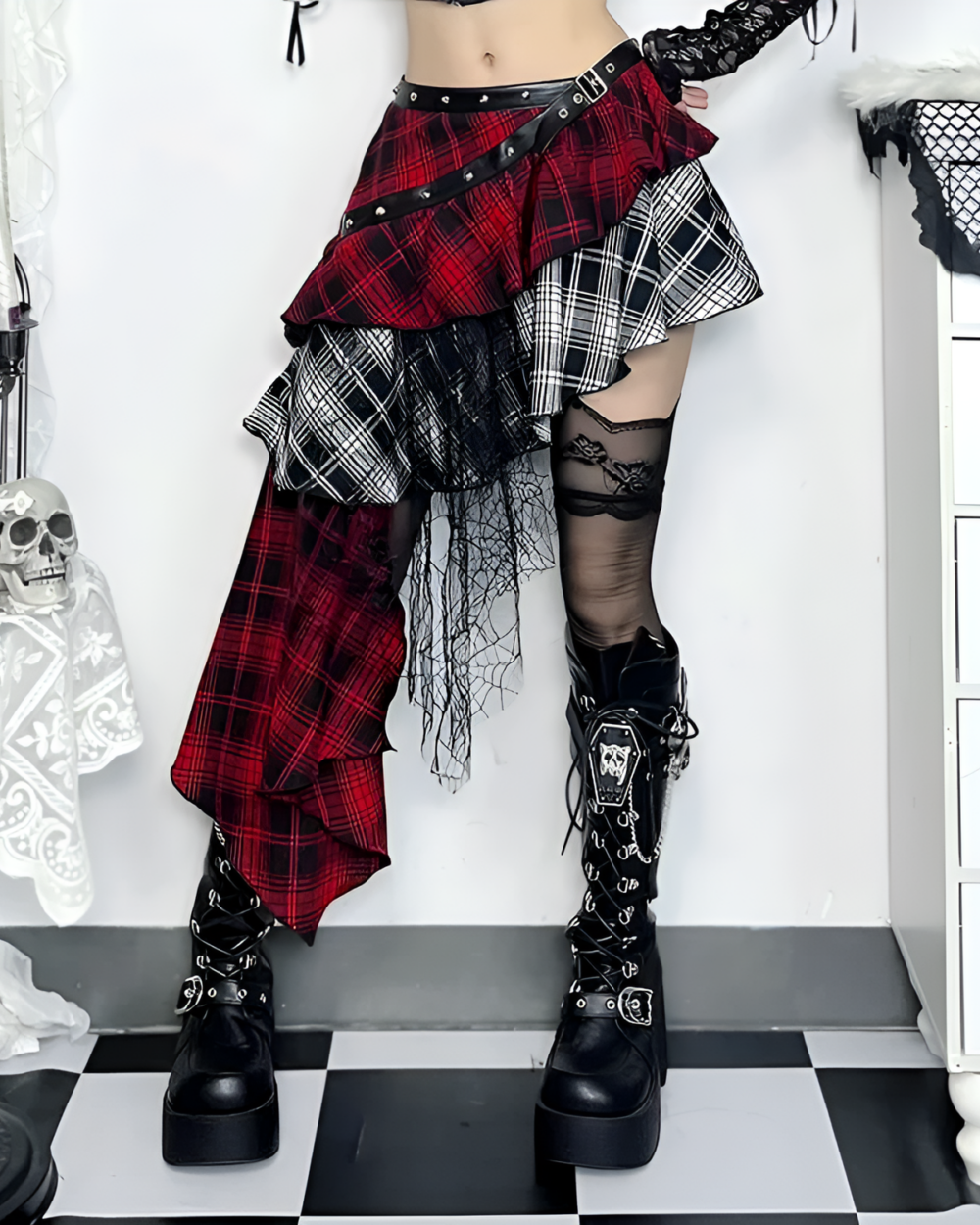 Model wearing a crimson and black pleated goth punk skirt with a layered design, black boots, and fishnet stockings.