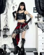 Model wearing a crimson and black pleated goth punk skirt with a black crop top and boots. This skirt features a punk aesthetic.