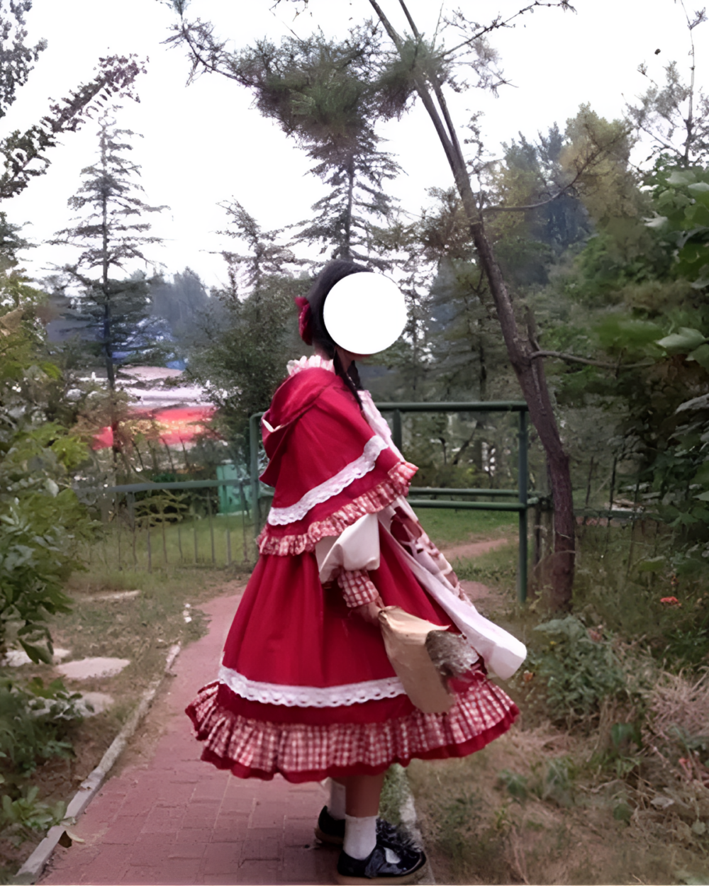 Person wearing a red Crimson Hood Berry Bear OP set with white lace details, photographed outdoors.