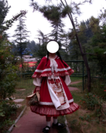Person wearing a Crimson Hood Berry Bear OP set in a forest. The dress features a red hooded cape and a printed skirt with bear motifs, showcasing the Berry Bear OP design.