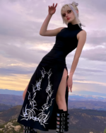 Model wearing a Dark Turtleneck Goth Dress with a high slit and tribal print, outdoors.
