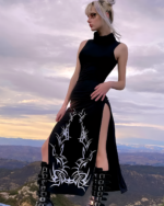 Model wearing a Dark Turtleneck Goth Dress with tribal print and side slits against a mountain backdrop.