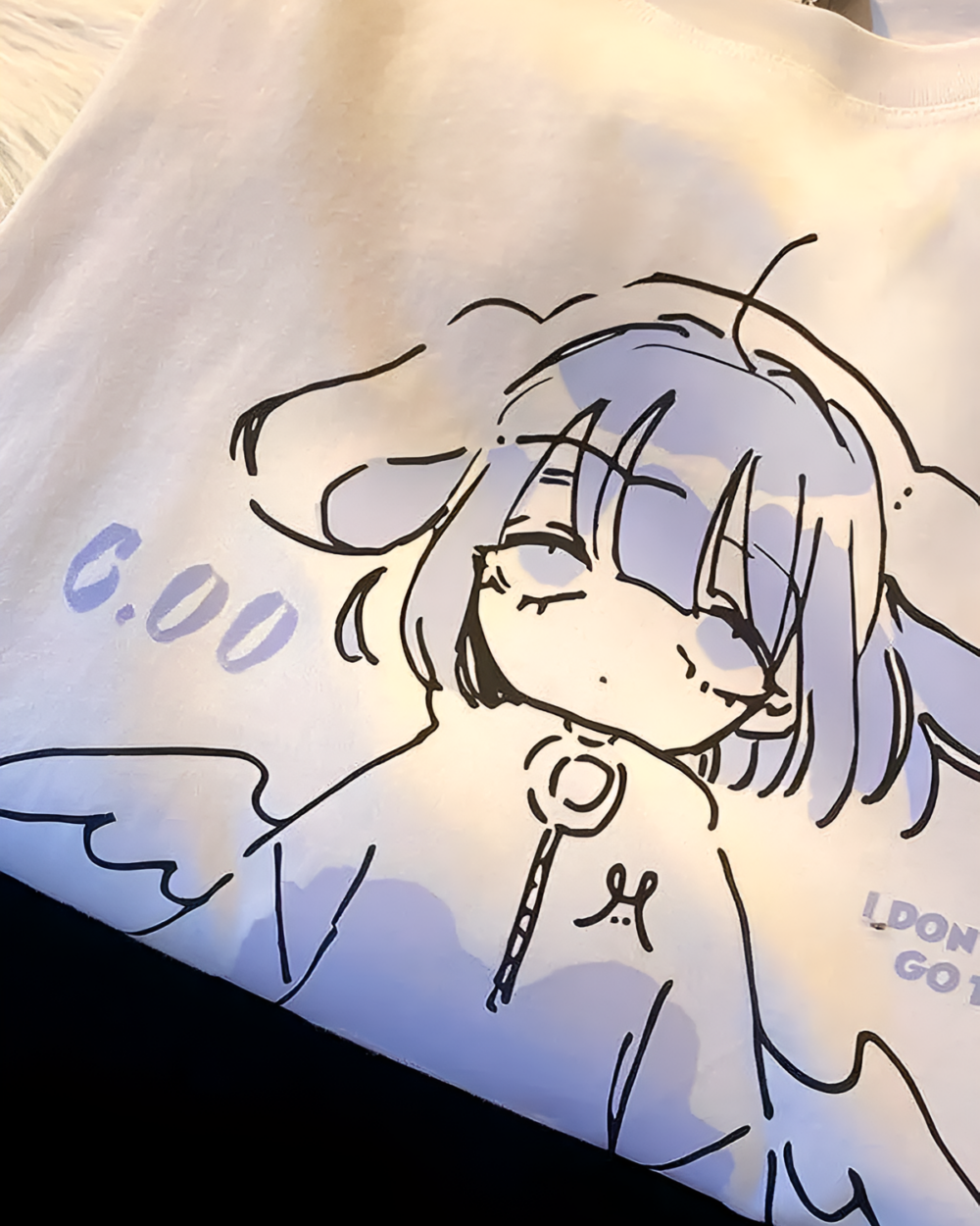 Close-up of a white tee featuring the Drowsy Cherub Graphic Tee design with a sketched cherub and text.