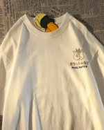 Close-up of a white t-shirt featuring the Dual Match Neko Bag T-Shirt design, with a cat and text on the front.