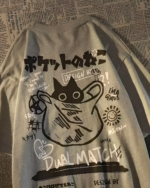 Close-up of a black Dual Match Neko Bag T-Shirt with a graphic design of a dinosaur and text on a textured background.