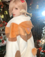 Person wearing an Extra Plushie FFXIV NEKO Coat with cat ears and a red ribbon. The FFXIV Neko Coat is fluffy and light brown.