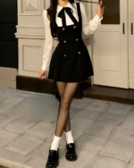 Black fake two-piece dress with a bib front and matching skirt, paired with tights and shoes.