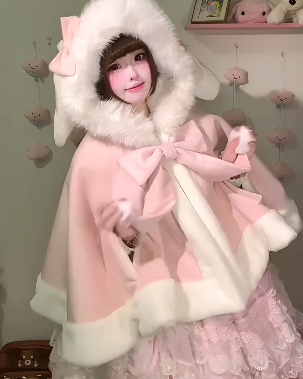 A person wearing a pink Fluffy Bunny Hooded Cloak with a white faux fur trim.