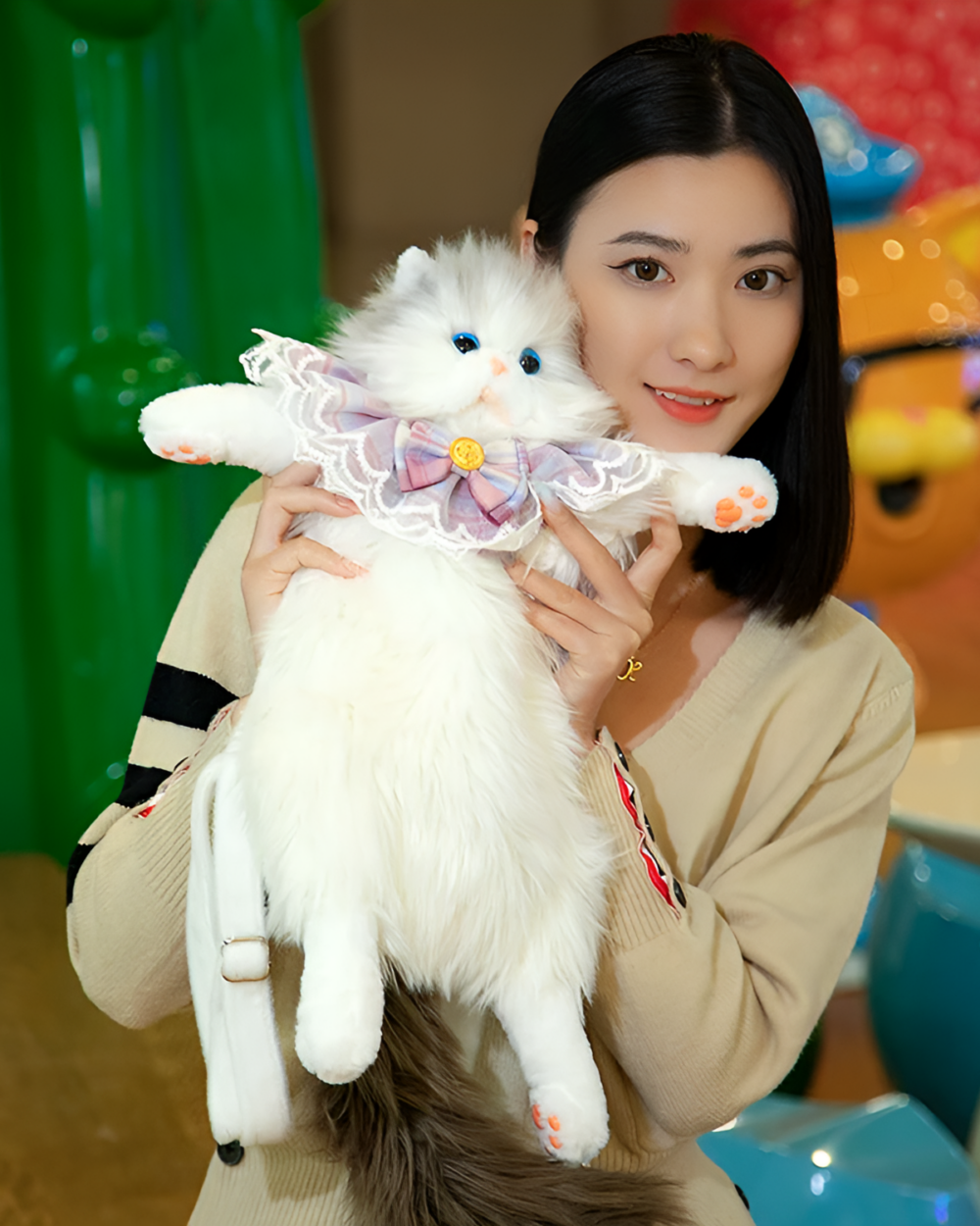 Woman holding a Fluffy Chonker Bag with a white stuffed cat wearing a pink collar.