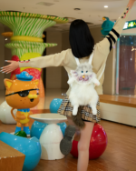 Person wearing a cute cat backpack with a white plush toy.