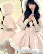 Model wearing a fluffy pink sweet lolita dress with a hooded cape and lace details. The dress features a winter aesthetic.
